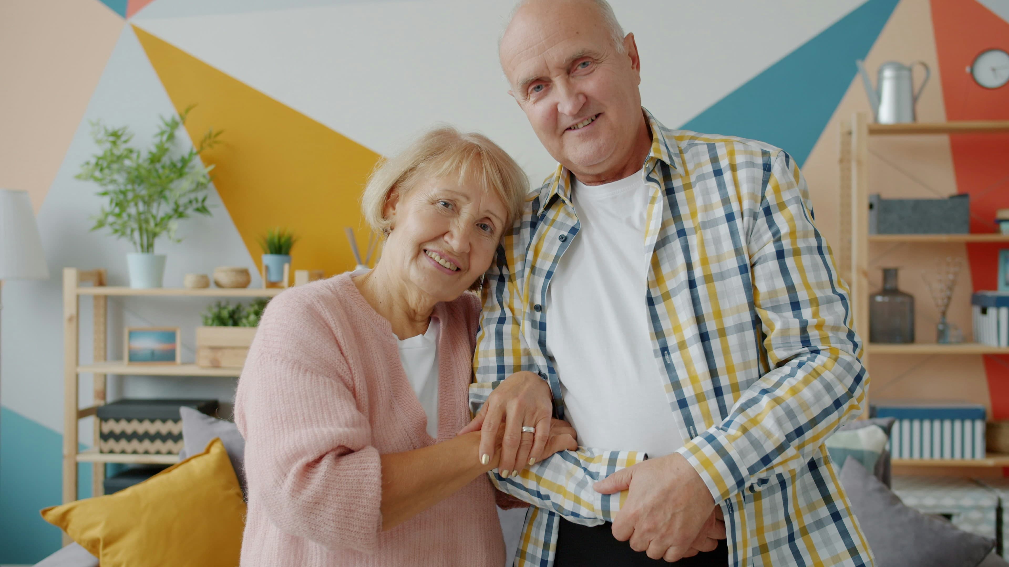 A smiling older couple holding hands at home